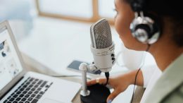 Woman speaking into a microphone in front of a notebook.