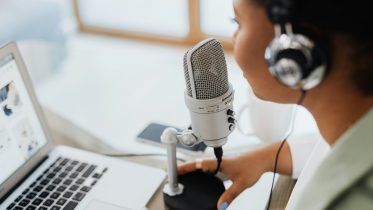 Woman speaking into a microphone in front of a notebook.
