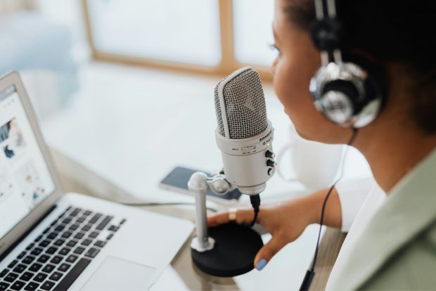 Woman speaking into a microphone in front of a notebook.